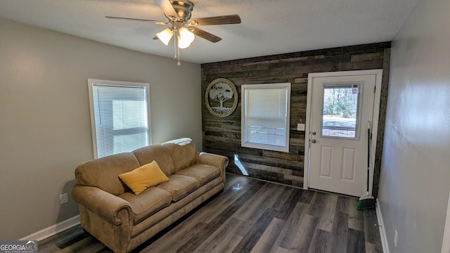 living room with dark hardwood / wood-style flooring, a textured ceiling, and wood walls