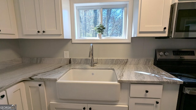 kitchen featuring sink, stainless steel appliances, white cabinets, and light stone countertops