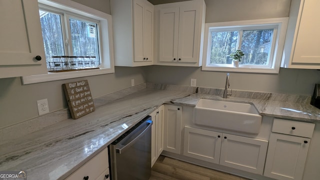 kitchen featuring sink, stainless steel dishwasher, white cabinets, and light stone countertops