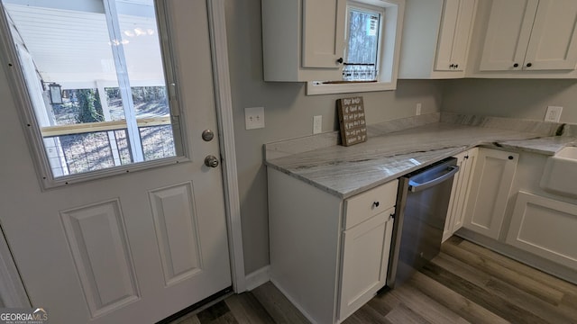 kitchen featuring light stone countertops, a healthy amount of sunlight, stainless steel dishwasher, and white cabinets