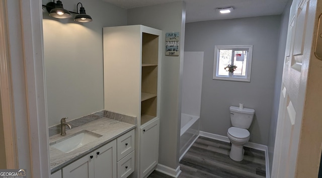 bathroom with hardwood / wood-style flooring, vanity, toilet, and a tub