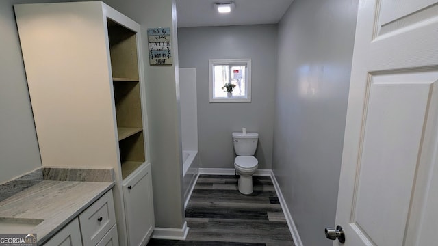 bathroom with vanity, hardwood / wood-style floors, toilet, and a tub to relax in