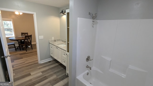 bathroom with hardwood / wood-style flooring, washtub / shower combination, and vanity