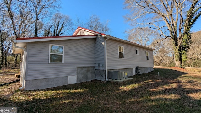 view of side of home with a lawn and central air condition unit