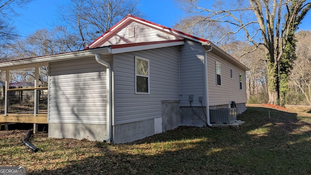 view of side of home with central AC unit and a lawn