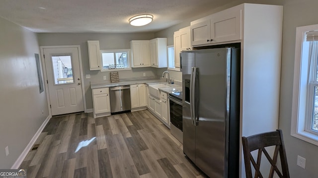 kitchen with a healthy amount of sunlight, stainless steel appliances, a textured ceiling, and white cabinets