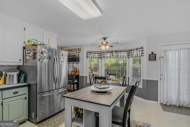 kitchen featuring stainless steel refrigerator, white cabinetry, ceiling fan, light tile patterned floors, and green cabinetry