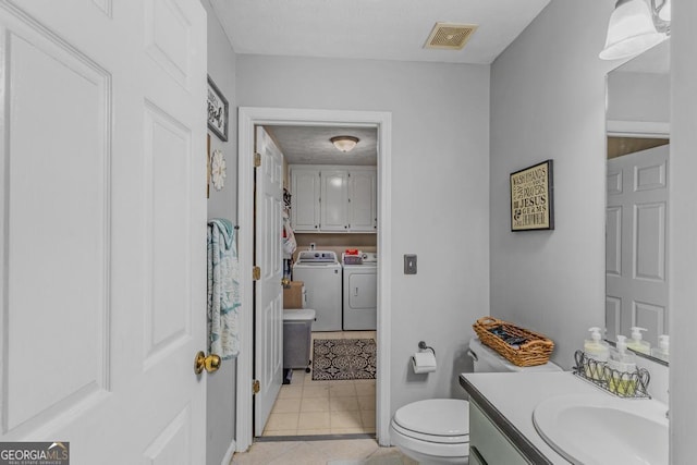 bathroom with tile patterned floors, washing machine and dryer, vanity, and toilet