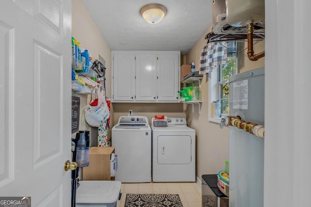 laundry area with washing machine and dryer, electric water heater, light tile patterned floors, and cabinets