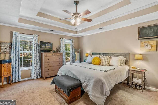 bedroom with a tray ceiling, ceiling fan, crown molding, and light colored carpet