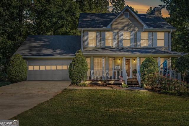 colonial home with a porch, a garage, and a yard