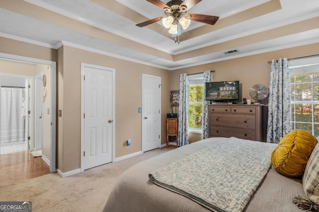 carpeted bedroom with multiple windows, a raised ceiling, ceiling fan, and crown molding