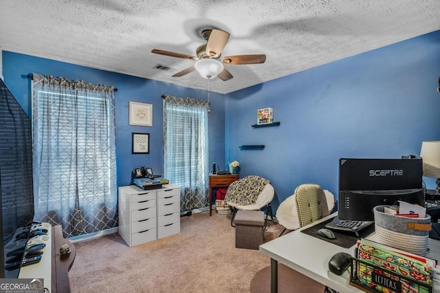 carpeted office space with ceiling fan and a textured ceiling