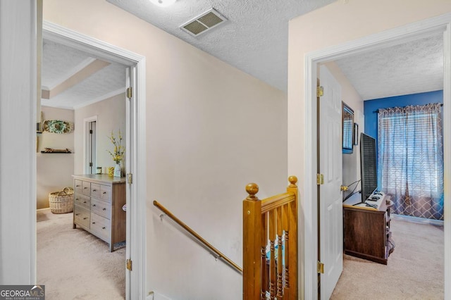 hall featuring a textured ceiling and light carpet