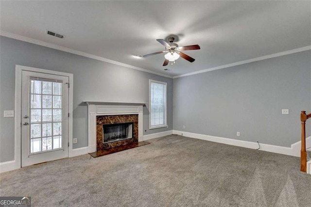 unfurnished living room featuring carpet, ceiling fan, a premium fireplace, and crown molding