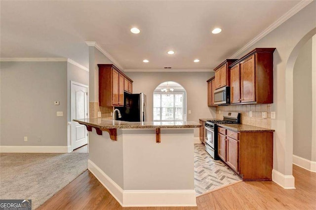 kitchen with decorative backsplash, stainless steel appliances, crown molding, and a breakfast bar area