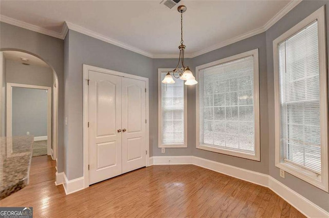 unfurnished dining area featuring light hardwood / wood-style floors, ornamental molding, and an inviting chandelier