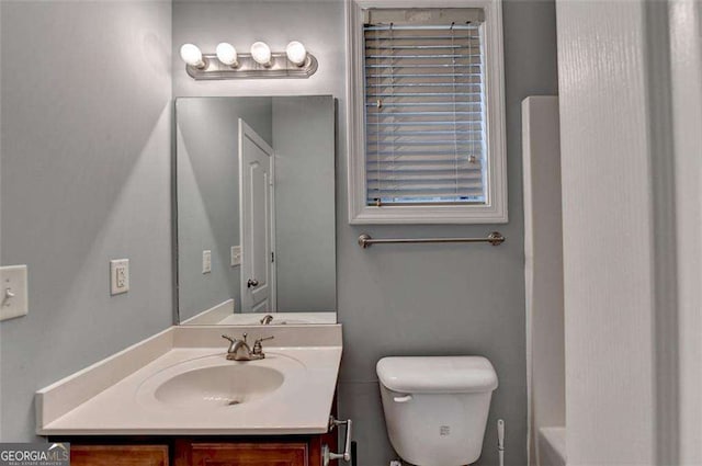 bathroom with vanity, a tub to relax in, and toilet