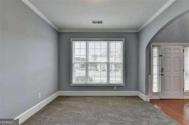 carpeted foyer featuring crown molding