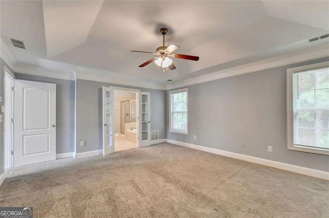 unfurnished bedroom featuring light carpet, french doors, ensuite bath, a raised ceiling, and ceiling fan