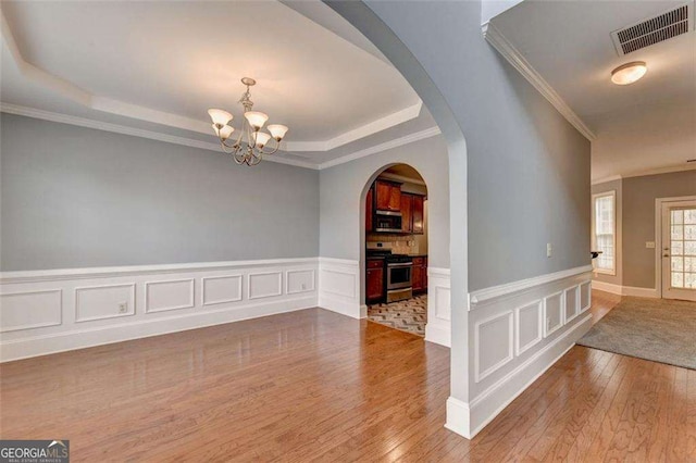 interior space featuring a raised ceiling, crown molding, a chandelier, and hardwood / wood-style flooring