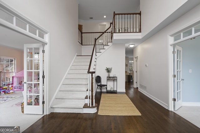 foyer entrance with dark hardwood / wood-style flooring, ornamental molding, a high ceiling, and french doors