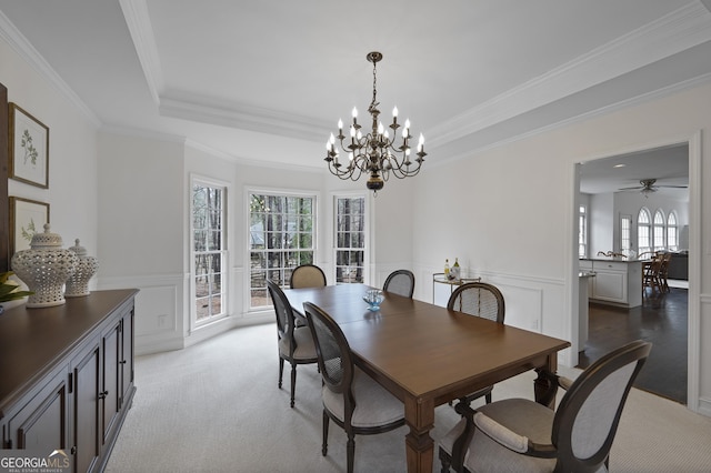 dining area featuring ceiling fan with notable chandelier, light colored carpet, and crown molding