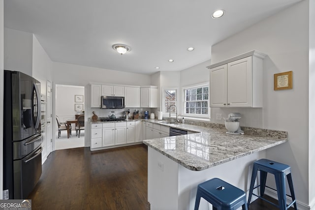 kitchen featuring white cabinets, appliances with stainless steel finishes, kitchen peninsula, and sink