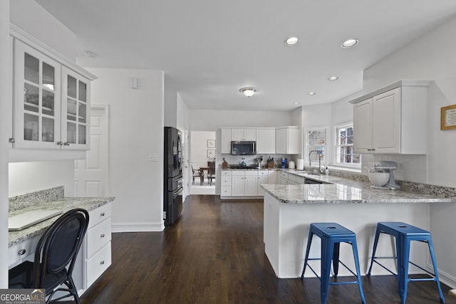 kitchen featuring white cabinets, light stone counters, kitchen peninsula, and appliances with stainless steel finishes