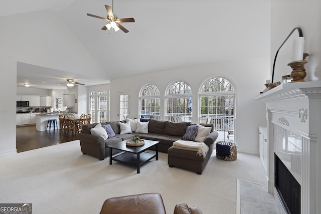 carpeted living room featuring a fireplace, high vaulted ceiling, plenty of natural light, and ceiling fan