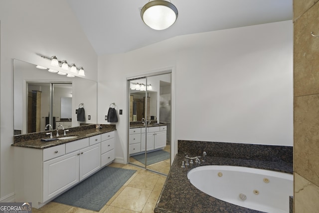 bathroom featuring tile patterned floors, vanity, a relaxing tiled tub, and lofted ceiling