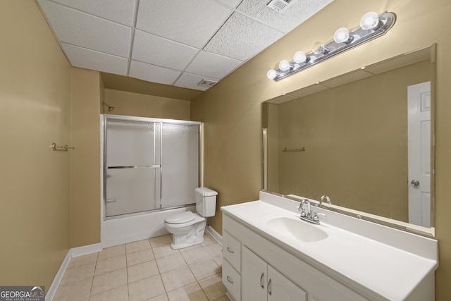 full bathroom featuring a paneled ceiling, vanity, shower / bath combination with glass door, tile patterned floors, and toilet