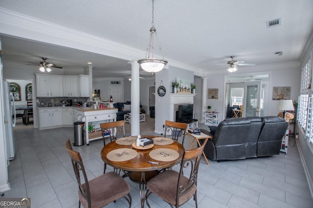 tiled dining space with ceiling fan, ornamental molding, and decorative columns