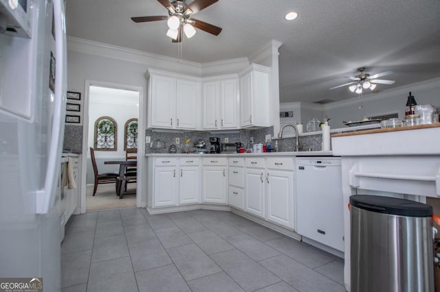 kitchen featuring backsplash, crown molding, white cabinets, and white appliances