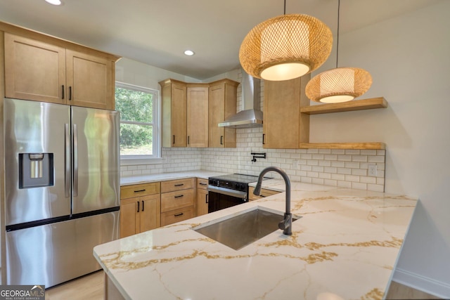 kitchen featuring kitchen peninsula, appliances with stainless steel finishes, wall chimney exhaust hood, sink, and hanging light fixtures