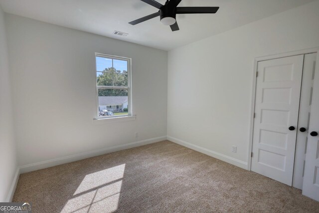 spare room with ceiling fan and light colored carpet