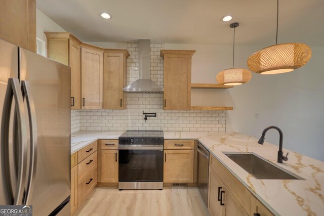 kitchen with sink, wall chimney exhaust hood, appliances with stainless steel finishes, tasteful backsplash, and decorative light fixtures