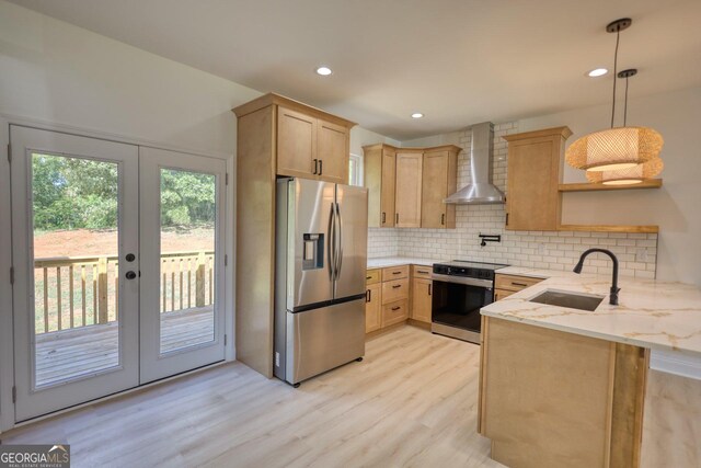 kitchen with appliances with stainless steel finishes, french doors, wall chimney exhaust hood, sink, and pendant lighting