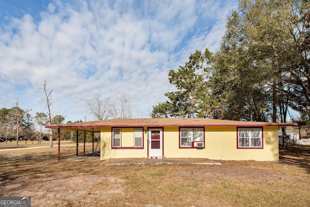 ranch-style home featuring a front lawn, a carport, and cooling unit