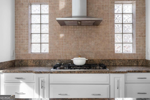 kitchen with white cabinetry, wall chimney exhaust hood, dark stone counters, and stainless steel gas cooktop