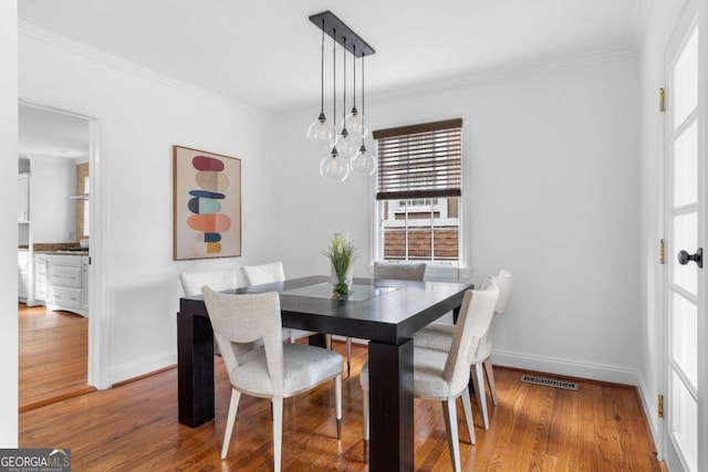 dining room featuring crown molding, a notable chandelier, and hardwood / wood-style flooring