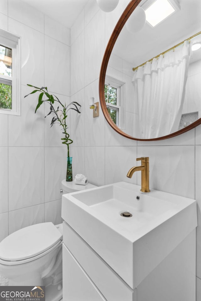 bathroom with vanity, toilet, and tile walls