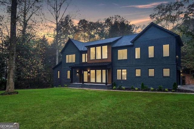 back house at dusk with a lawn