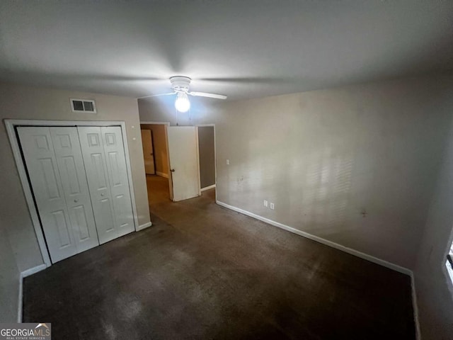 unfurnished bedroom with dark colored carpet, a closet, and ceiling fan