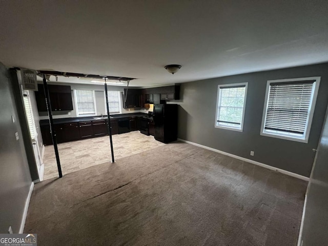 interior space with light carpet, black fridge, and a healthy amount of sunlight