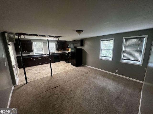 kitchen featuring light carpet and black fridge