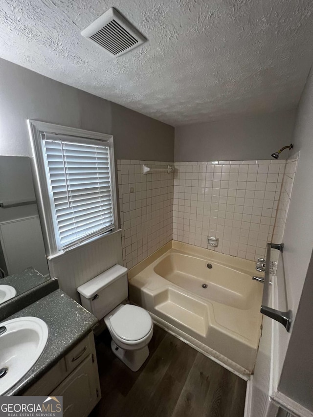 full bathroom with vanity, wood-type flooring, a textured ceiling, and shower / tub combination