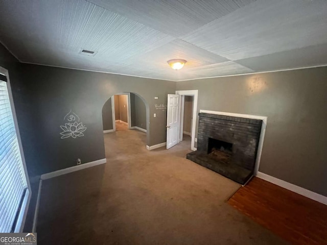 unfurnished living room featuring wood-type flooring and a brick fireplace