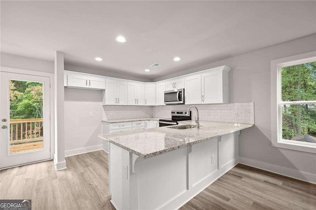 kitchen with backsplash, sink, white cabinets, and stainless steel appliances