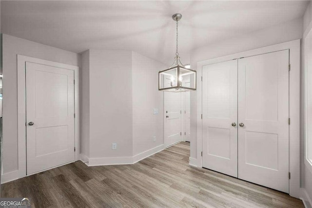 unfurnished dining area featuring hardwood / wood-style flooring and a notable chandelier